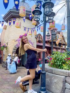 a woman is posing next to a lamp post in front of a building with decorations on it