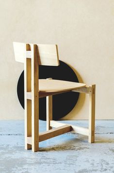 a wooden chair sitting on top of a floor next to a black plate and wall