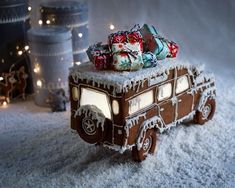 a toy truck covered in snow with presents on the roof and lights around it's sides