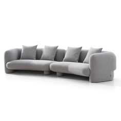 a gray couch with many pillows on the back and sides, sitting in front of a white background