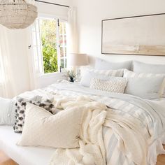 a bed with white sheets and pillows in a bedroom