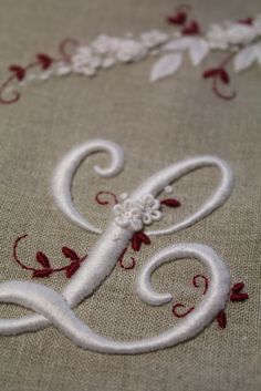 an embroidered monogram with red and white flowers on it is shown in close up