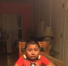 a young boy sitting at a table with food in front of him