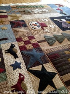 a quilt made to look like stars and other things on the bed with wood flooring