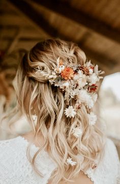 a woman with long blonde hair and flowers in her hair is wearing a white dress