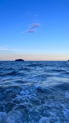 the ocean is blue and choppy with small islands in the distance under a cloudless sky