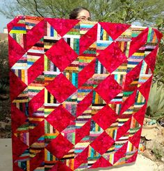 a woman standing next to a red quilt