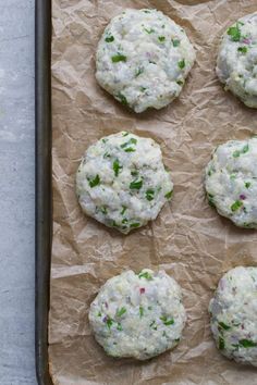 six crackers covered in cheese and green onions on top of parchment paper, ready to go into the oven