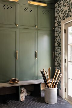 a room with green cabinets and a white dog sitting on the floor next to it