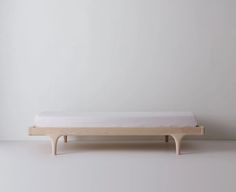 a small bed sitting on top of a white floor next to a wooden frame and wall