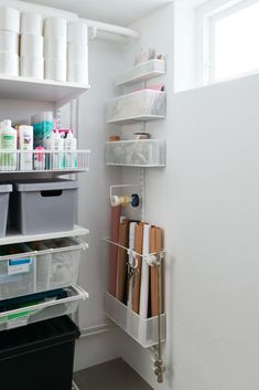 an organized pantry with white shelves and plastic bins