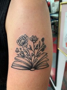 an open book with flowers and leaves on the inside of its cover - up tattoo