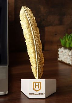 a golden feather on top of a desk next to a computer