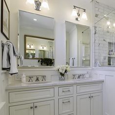 a white bathroom with double sinks and mirrors