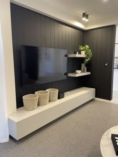 a living room with a flat screen tv on the wall and two baskets in front of it