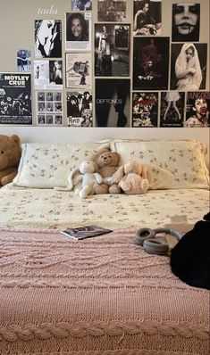 there is a bed with many pictures on the wall above it and two teddy bears