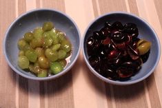 two bowls filled with green and black olives next to each other on a table