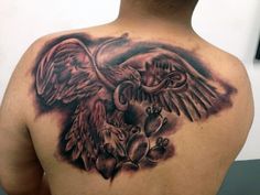 the back of a man's shoulder with an owl and heart tattoo on it