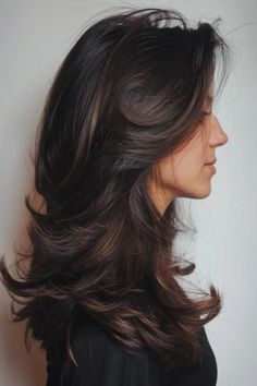 Woman with dark, wavy hair in a layered style, seen in profile against a plain background. Partial Lowlights For Dark Hair, Layered Dimensional Brunette, Black Hair With Dark Brown Lowlights, Dark Brown Hair Soft Highlights, Brown Hair Brown Balayage, Sun Kissed Balayage Black Hair, Dark Brown Partial Highlights, Face Framing Lowlights Dark Brown, Rich Brunette Hair With Dimension