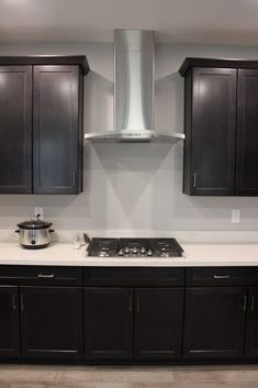 a stove top oven sitting inside of a kitchen next to black cupboards and cabinets