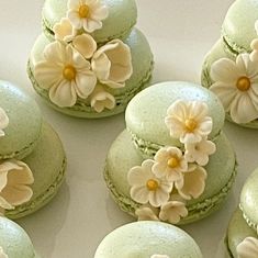 there are many green macaroons with white flowers on them and one has yellow centers