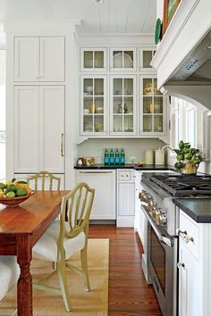 a kitchen with white cabinets and wooden table in front of an oven, stove top