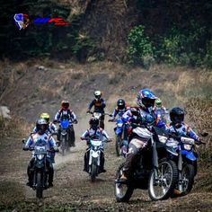 a group of motorcyclists riding down a dirt road