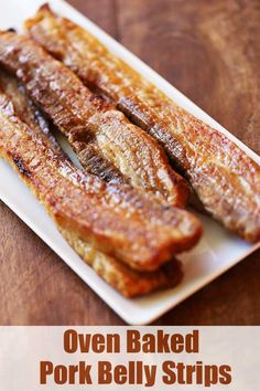 some bacon is on a white plate on a wooden table and it looks like they have been cooked in the oven