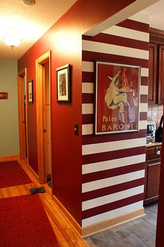 a red and white striped hallway leading to a kitchen with wood cabinets on either side