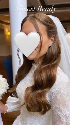 a woman with long hair holding a white flower and wearing a heart shaped brooch