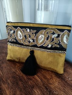 This silk kutnu clutch will bring elegance to your style. It will be chic with jeans or dresses and you may use this clutch bag both day and night. This clutch bag is perfectly handmade with high quality handwoven silk kutnu fabric. Designed with a silk bohemian embroidery and tassel. Clutch has an interfacing and a padding inside to stand upright. Closes with a zipper. This bag is designed to fit all the things you need for comfortable everyday busy life. There will be enough space for smart ph Festive Gold Bag With Tassels, Elegant Festival Bags With Tassels, Bohemian Pouch Clutch For Festive Occasions, Handmade Bohemian Clutch For Festive Occasions, Gold Bohemian Embroidered Clutch, Bohemian Gold Evening Bag, Festive Bohemian Handmade Clutch, Bohemian Clutch With Zari Work, Bohemian Embroidered Clutch For Festive Occasions