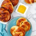 bread rolls and butter on a blue plate next to two bowls of dip sauces