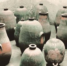 many green and brown vases sitting on the ground