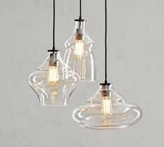 three clear glass pendant lights hanging from a ceiling