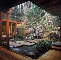 an outdoor garden with a pond and wooden decking, surrounded by rocks and trees