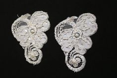 two white lace appliques on black background