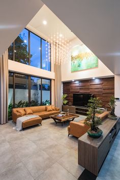 a living room with couches, tables and plants in the middle of the room