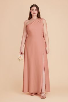 a woman in a long pink dress with one side slit and an asymmetrical neckline