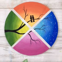 a painted plate with two birds sitting on a tree branch in front of a multi - colored background