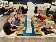 a group of people sitting around a table with food on it and plates in front of them