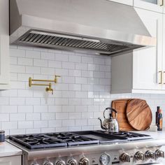 a stove top oven sitting inside of a kitchen next to white cabinets and counter tops