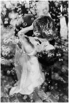 a black and white photo of a woman blowing bubbles in the air with her hands