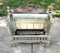 an old metal fire place sitting on top of a cement ground next to grass and bushes