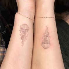 two people with matching tattoos on their arms holding each other's hands and one has a jellyfish tattoo on its arm