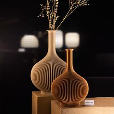 two vases sitting on top of boxes with flowers in them, one is brown and the other is beige