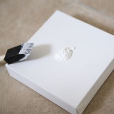 a white box with a piece of black and white paint sticking out of it's side