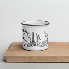 a white and black coffee cup with the statue of liberty on it sitting on top of a wooden tray