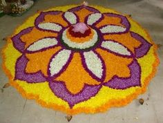 a large flower design on the ground with candles in it's center and flowers all around