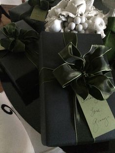 a present wrapped in black paper and tied with green ribbon on top of a table