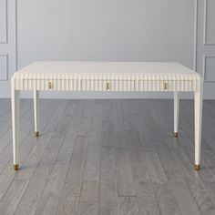 a white table with gold legs on a wooden floor